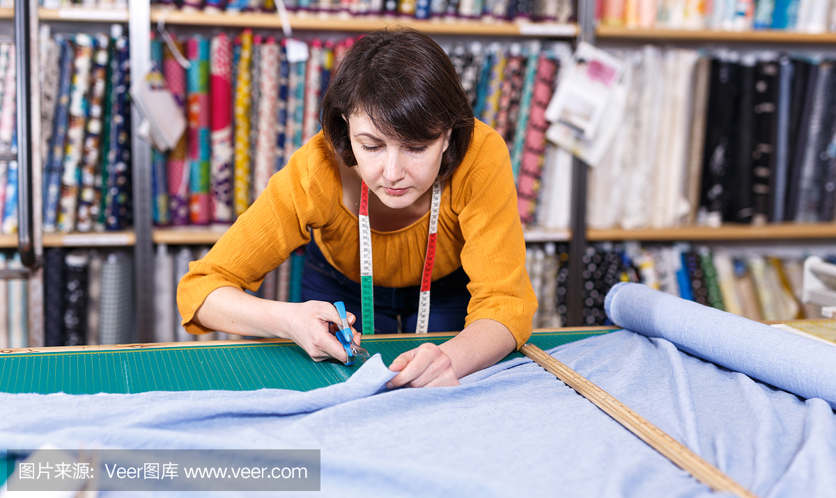 女售货员测量并剪下一块纺织品